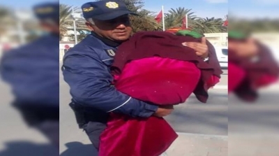 عون أمن يحمل عجوزا بين ذراعيه ليساعدها على قطع الطريق (صور)